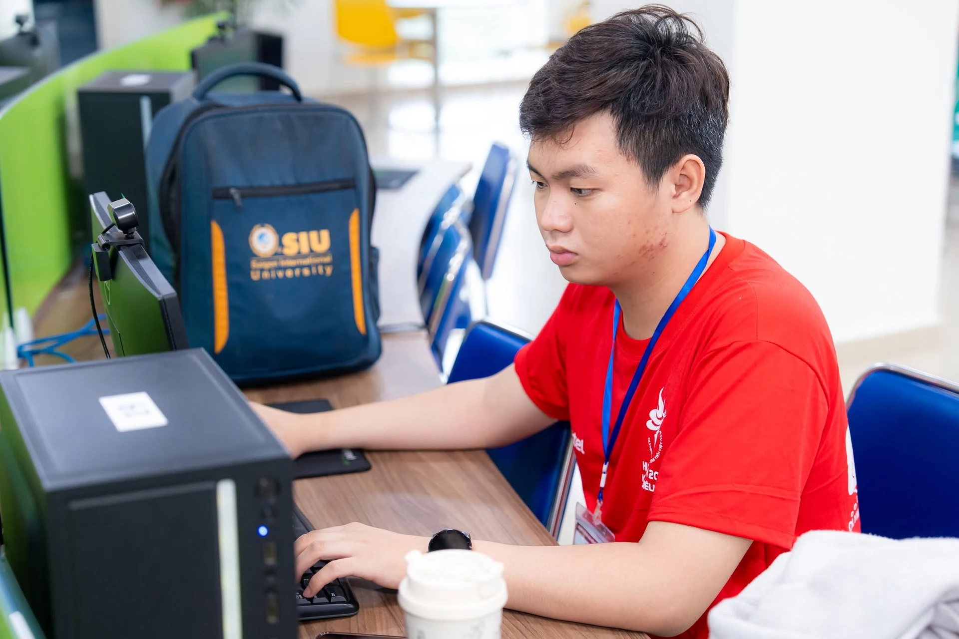 Một thành viên áo đỏ làm việc với máy tính xách tay, bên cạnh là ba lô SIU.
