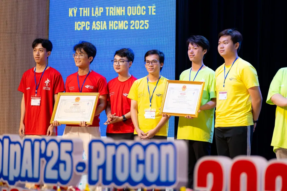 Team members with award certificates on stage at OLP and ICPC Asia HCMC 2025.